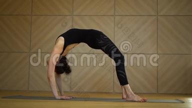 年轻迷人的女子练瑜伽在轻<strong>简约</strong>工作室教室。做乌尔德瓦·达努拉萨纳和伸<strong>展</strong>运动的女孩